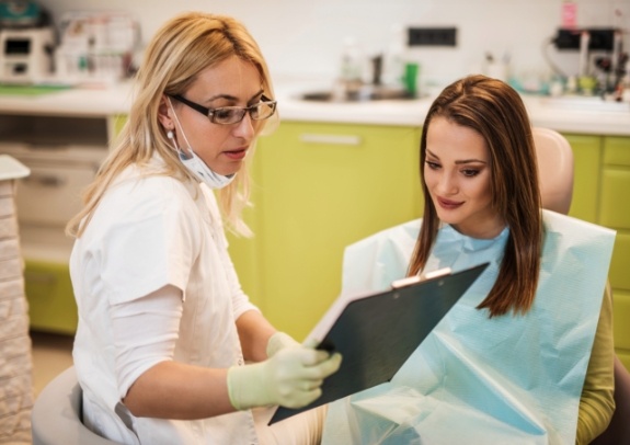 Dental team member and patient reviewing dentistry treatment chart