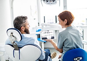 Smiling dental assistant and patient looking at X-ray
