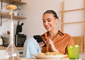 Woman smiling while looking at phone at home