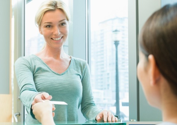 Smiling dental patient paying for dentistry treatment