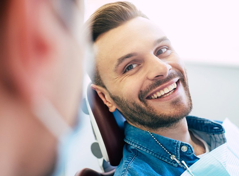 Man in denim shirt in dental chair smiling