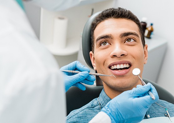 Man in blue shirt smiling at dentist about to examine his teeth
