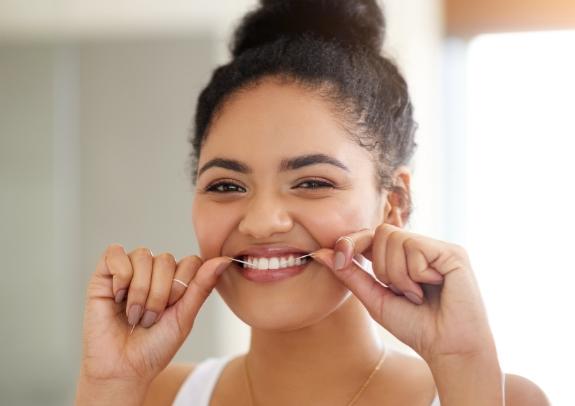 Woman flossing teeth and enjoying benefits of clearcorrect