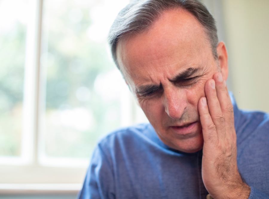 Man in need of emergency dentistry holding jaw in pain