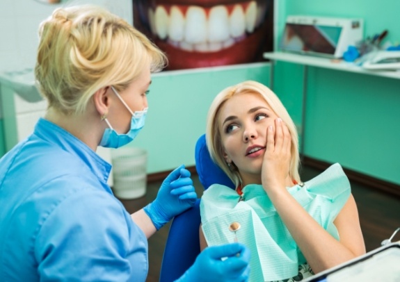 Woman holding cheek during emergency dentistry visit