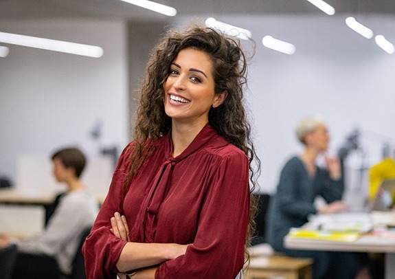 Businesswoman in office smiling with arms folded