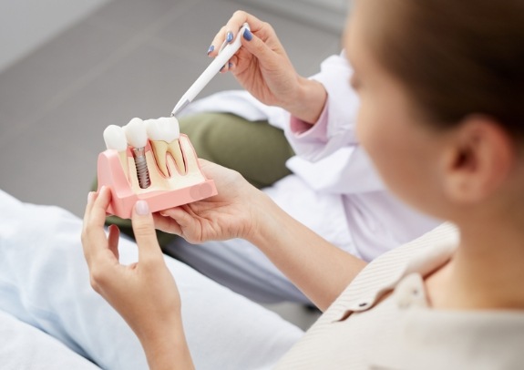 Dentist and patient looking at dental implant model