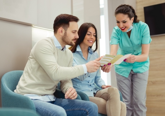 Dental team member and patients discussing dental insurance benefits