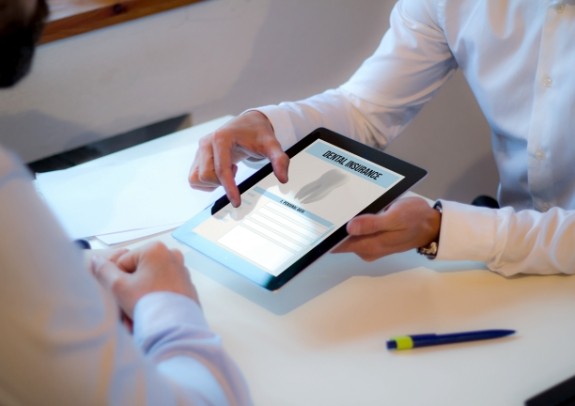 Dental team member and patient reviewing dental insurance forms on tablet computer