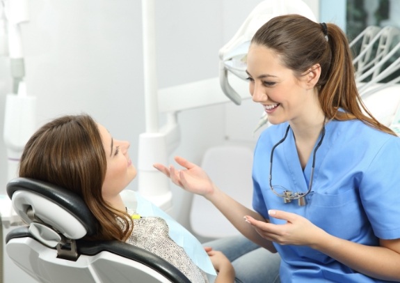 Dental team member talking to patient during dental checkup and teeth cleaning