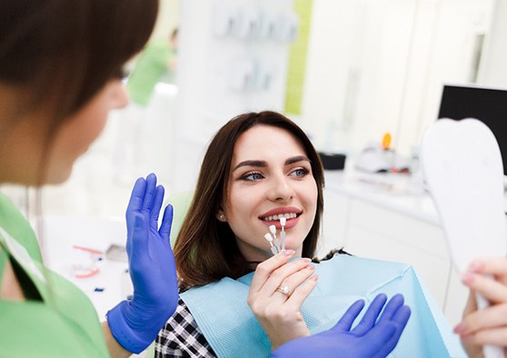 Woman in dentist’s chair holding test veneers